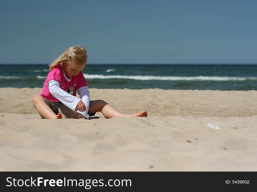 Portrait of little girl sitting  on the  beach over blue sky. Portrait of little girl sitting  on the  beach over blue sky