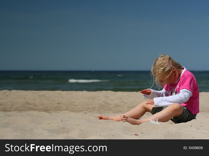 Portrait of little girl sitting  on the  beach over blue sky. Portrait of little girl sitting  on the  beach over blue sky
