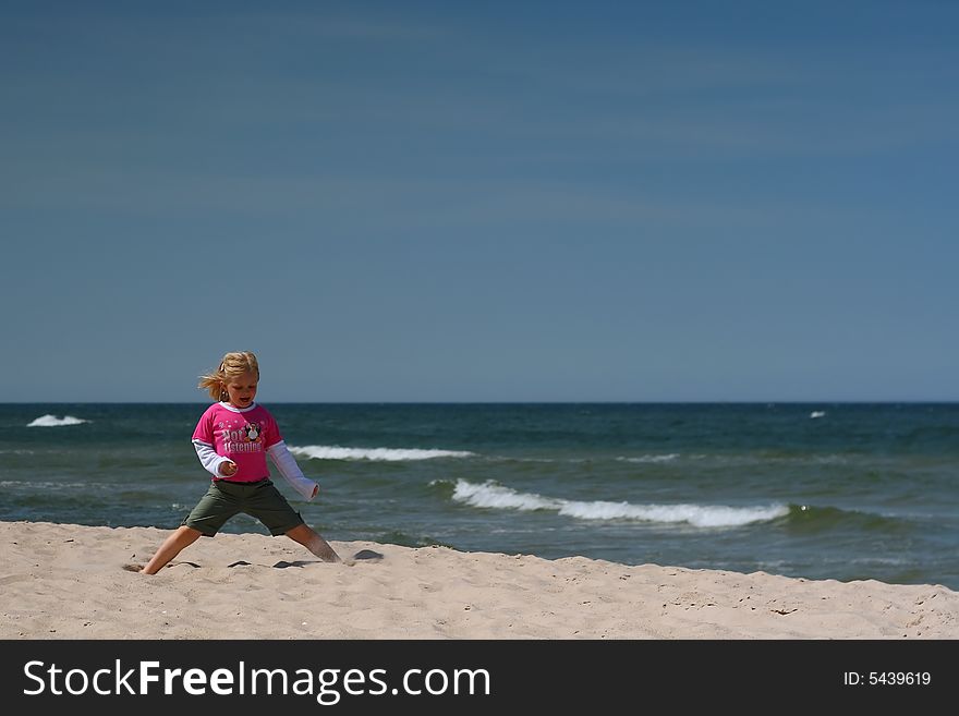 Portrait of little girl sitting  on the  beach over blue sky. Portrait of little girl sitting  on the  beach over blue sky