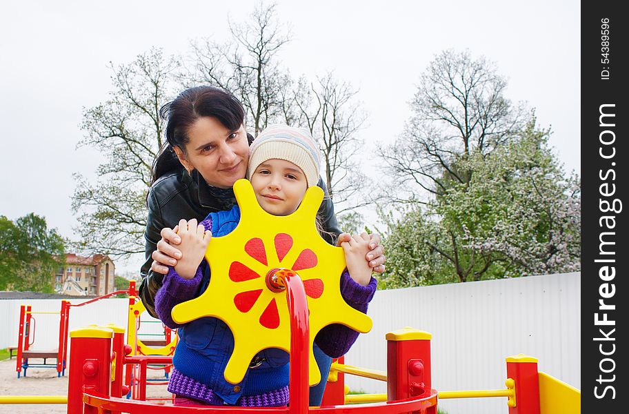 Mom plays with her daughter at the playground on a toy ship on spring day. Mom plays with her daughter at the playground on a toy ship on spring day