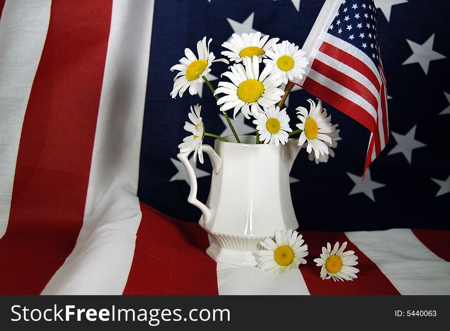 Bouquet of wild field daisies in a vintage creamer on a flag. Bouquet of wild field daisies in a vintage creamer on a flag.