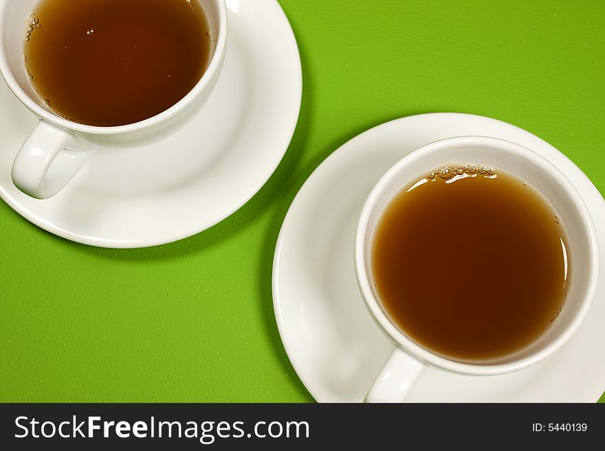 Cups of tea on green background