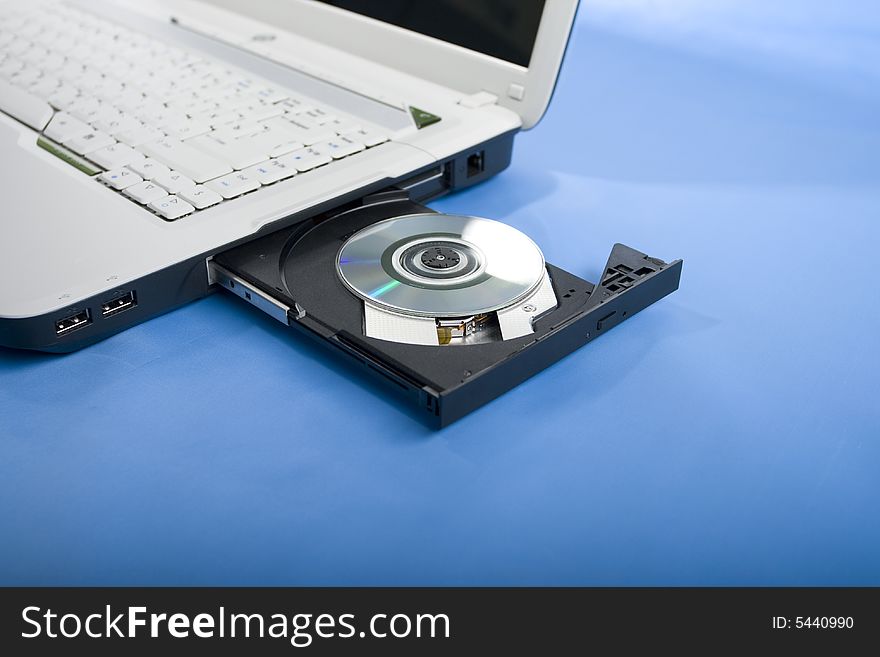 Laptop disk drive, keyboard, blue background