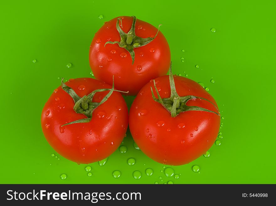 Three tomatoes on green, drops