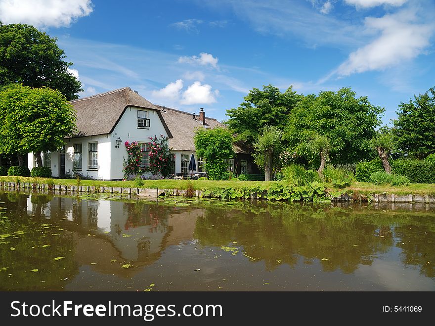 Old farm house with a reflection in the water on a summer day.