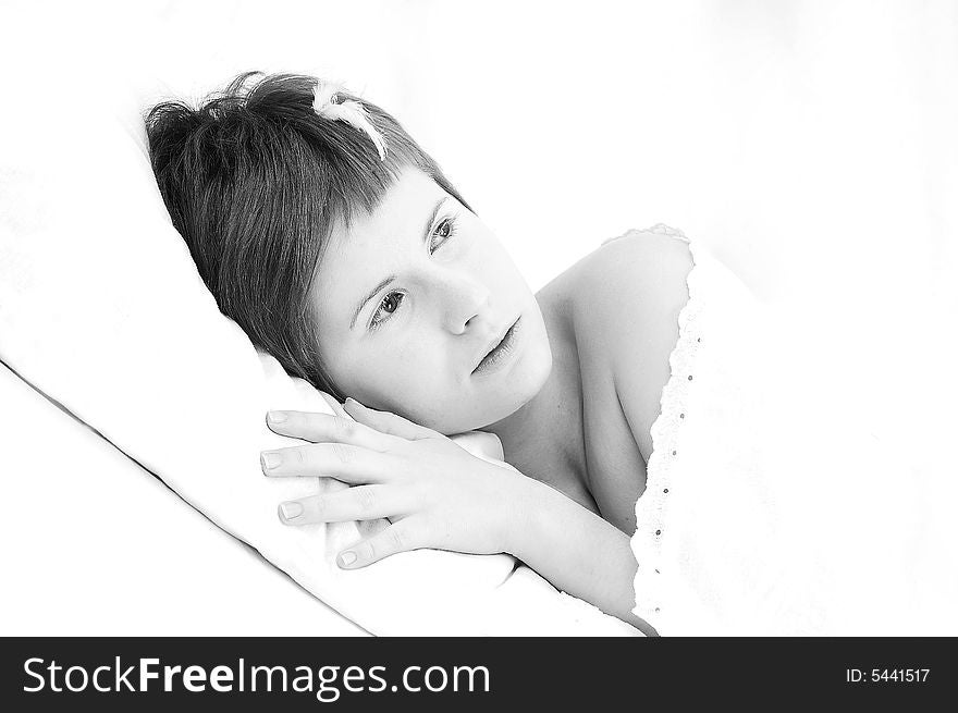 Portrait of short haired girl with white eyelashes and a tiny feather on her head, lying down on a pillow (diagonal composition, high key lightning)