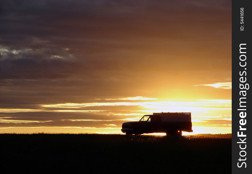 Old vehicle in silhouette at sunset in a field. Old vehicle in silhouette at sunset in a field