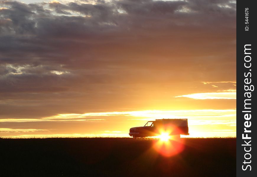 Old vehicle in silhouette at sunset in a field. Old vehicle in silhouette at sunset in a field