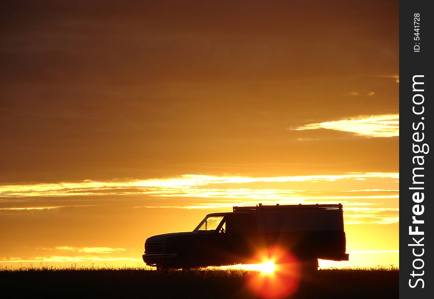 Old vehicle in silhouette at sunset in a field. Old vehicle in silhouette at sunset in a field
