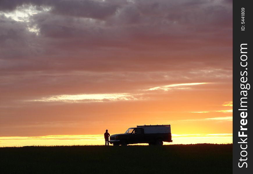 Old vehicle in silhouette at sunset in a field. Old vehicle in silhouette at sunset in a field