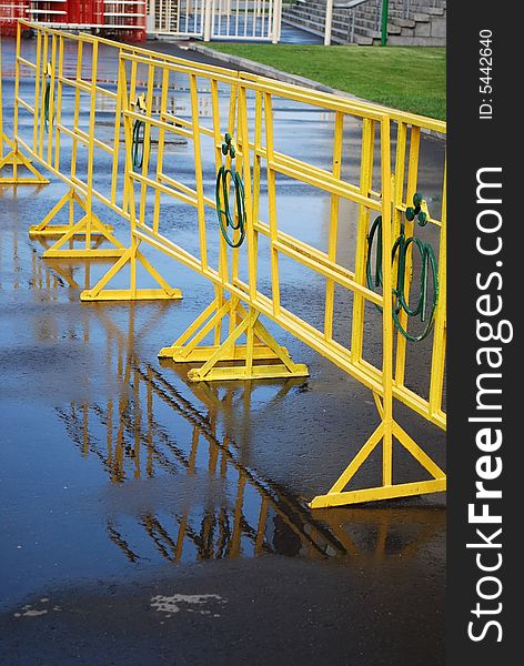 Bright yellow crowd control fence with reflection after rain. Bright yellow crowd control fence with reflection after rain