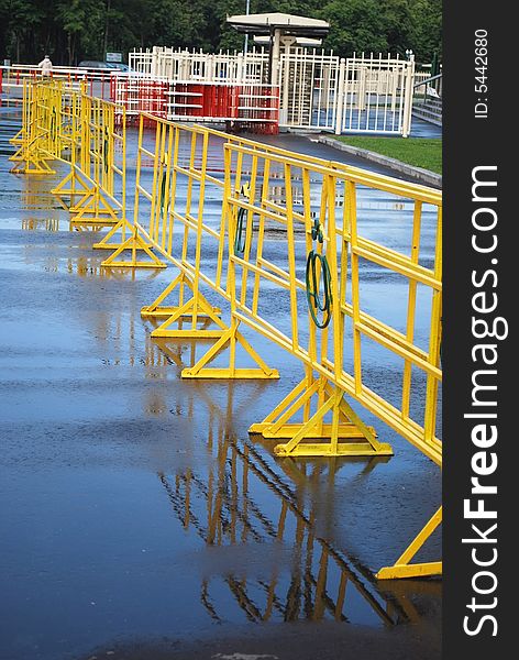 Bright yellow crowd control fence with reflection after rain. Bright yellow crowd control fence with reflection after rain