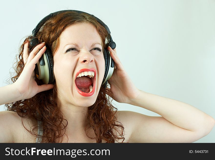 The girl in headphones shouts on a white background. The girl in headphones shouts on a white background