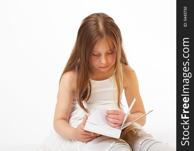 The little girl with long hair sits and reads the book. The little girl with long hair sits and reads the book