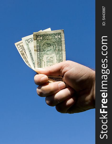 Hand with dollar bills of various denominations on sky background. Hand with dollar bills of various denominations on sky background