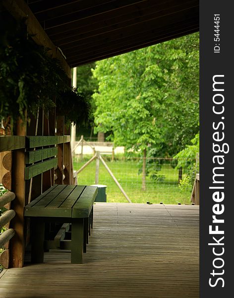 Wooden bench and terrace with beautiful greenery in background.
