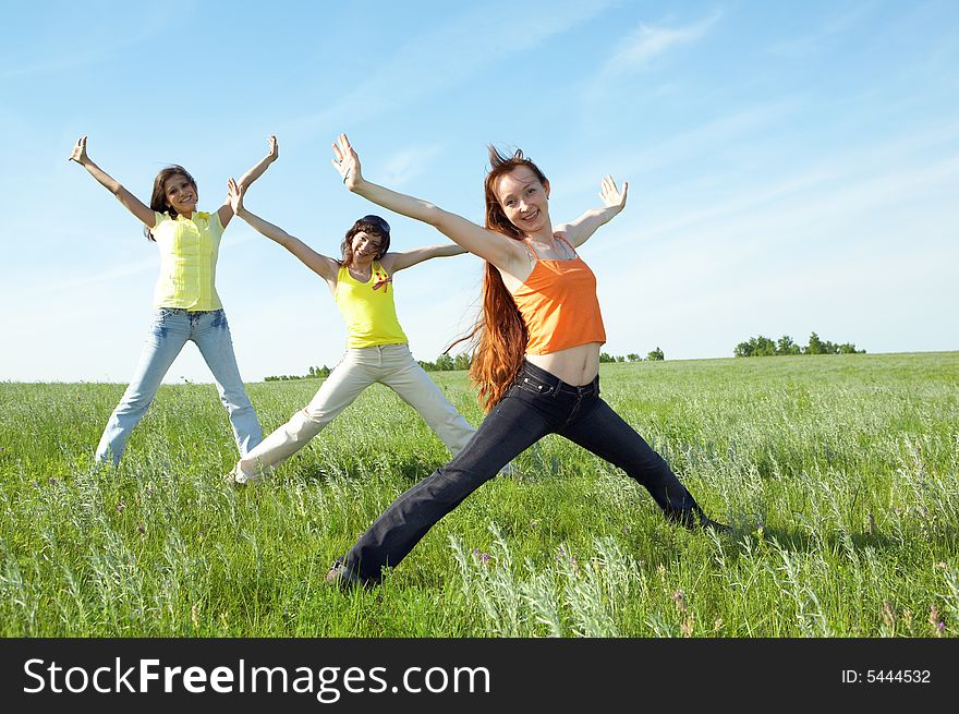 Three girlfriend in green field under blue sky