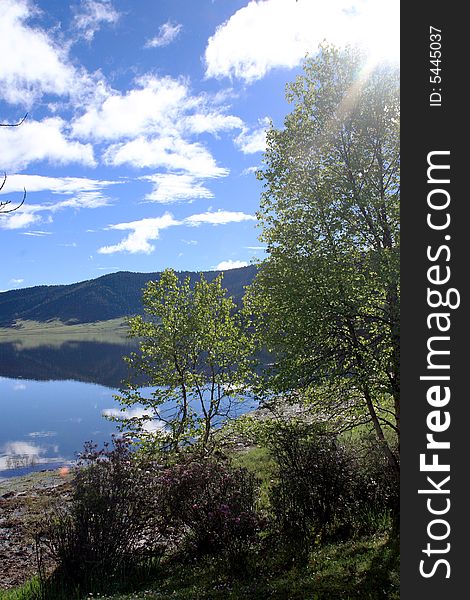 Lake in mountains surrounded by  woods and the cloudy sky above it. Lake in mountains surrounded by  woods and the cloudy sky above it.