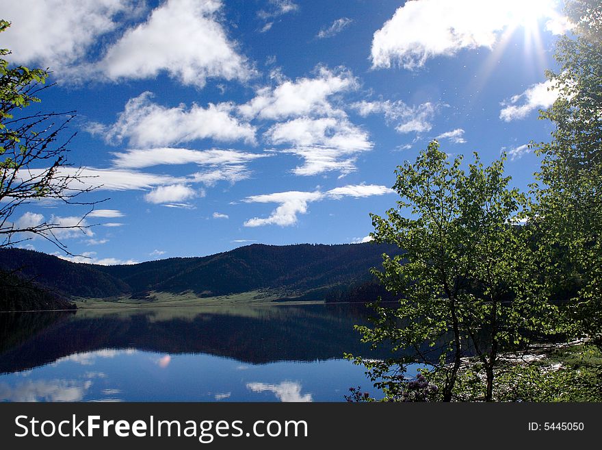 Lake in mountains surrounded by  woods and the cloudy sky above it. Lake in mountains surrounded by  woods and the cloudy sky above it.