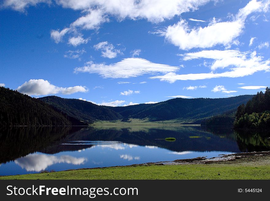 Lake in mountains surrounded by  woods and the cloudy sky above it. Lake in mountains surrounded by  woods and the cloudy sky above it.