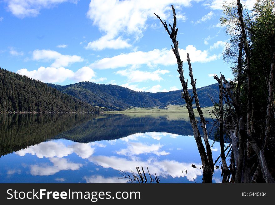 Lake in mountains surrounded by  woods and the cloudy sky above it. Lake in mountains surrounded by  woods and the cloudy sky above it.