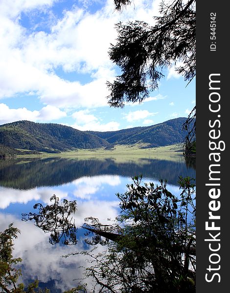 Lake in mountains surrounded by  woods and the cloudy sky above it. Lake in mountains surrounded by  woods and the cloudy sky above it.