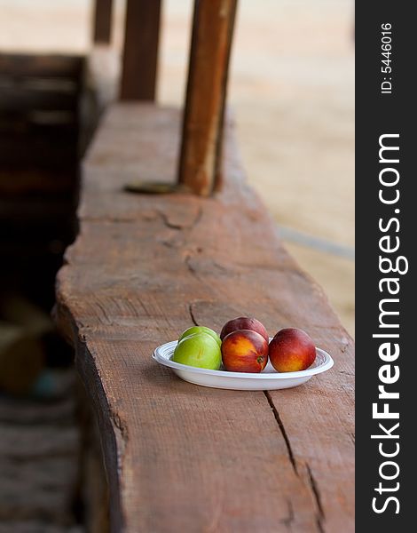 The red and green peaches in the plastic dish. The red and green peaches in the plastic dish.