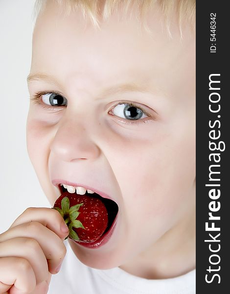A small boy eating  strawberry