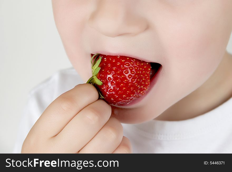 A small boy eating  strawberry