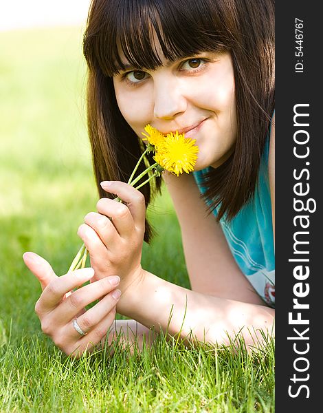 Girl with dandelions lying on the green lawn