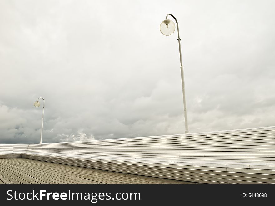 2 lamps on a peer in sopot with a long white bench