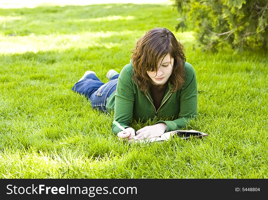 Young student reading on the grass in the park. Young student reading on the grass in the park.