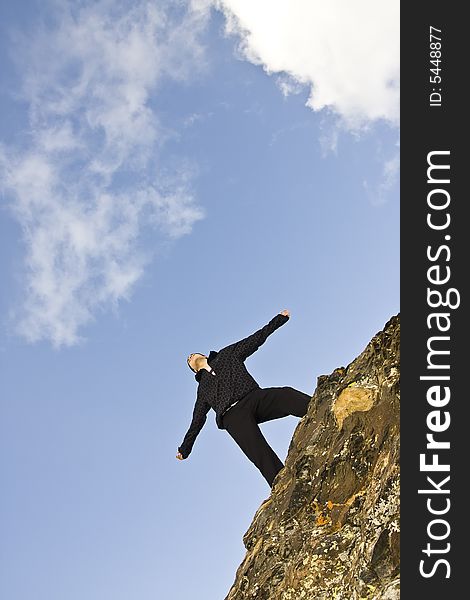 Young man on the rocks in defiant gesture. Young man on the rocks in defiant gesture