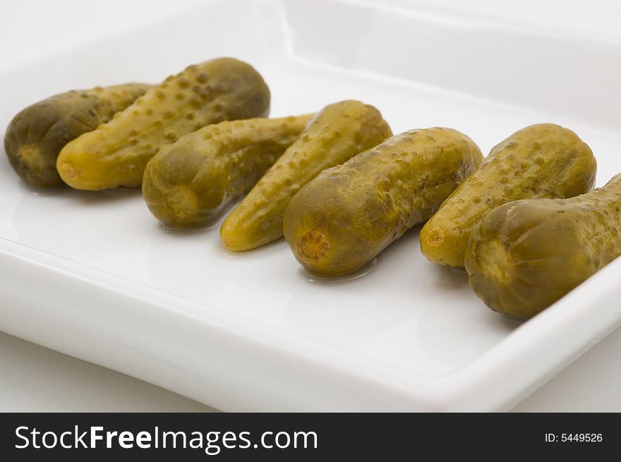 Fresh dill pickles on plate, isolated, studio shot.