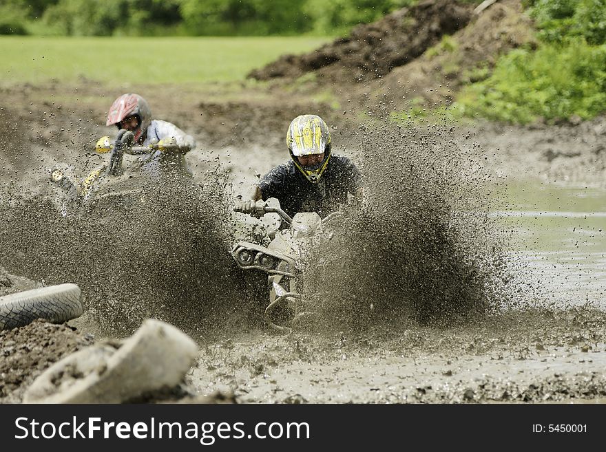 Men race with ATVs in muddy waters. Men race with ATVs in muddy waters.