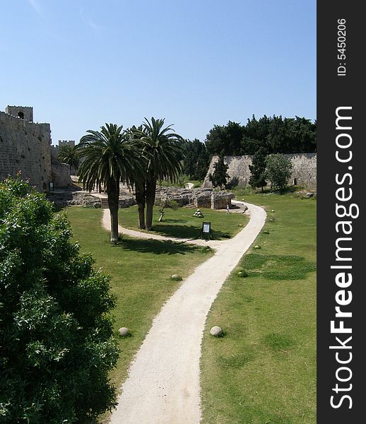 Road and palms inside a middle ages castle in greece