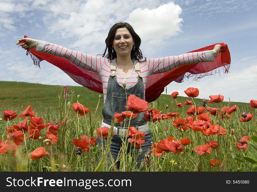 Beautiful girl standing among red poppies and holding a red scarf. Beautiful girl standing among red poppies and holding a red scarf