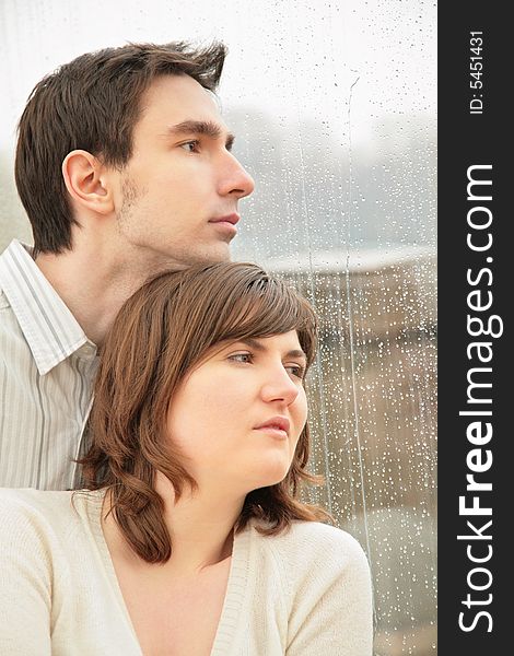 Boy with the girl against  background of  wet window