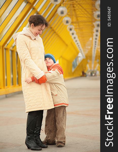 Son embraces mother on yellow footbridge. Son embraces mother on yellow footbridge