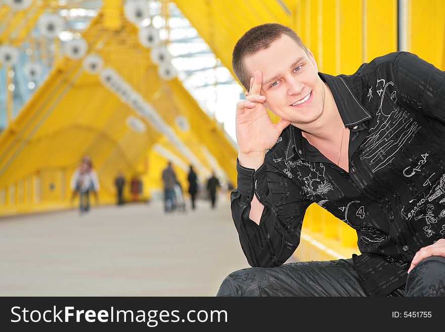 Smiling guy sits on yellow footbridge. Smiling guy sits on yellow footbridge