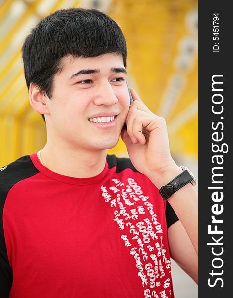 Young man talks by  cell phone on footbridg