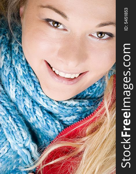 Smiling young woman wearing red jacket and blue scarf. Autumn or winter fashion. Smiling young woman wearing red jacket and blue scarf. Autumn or winter fashion.
