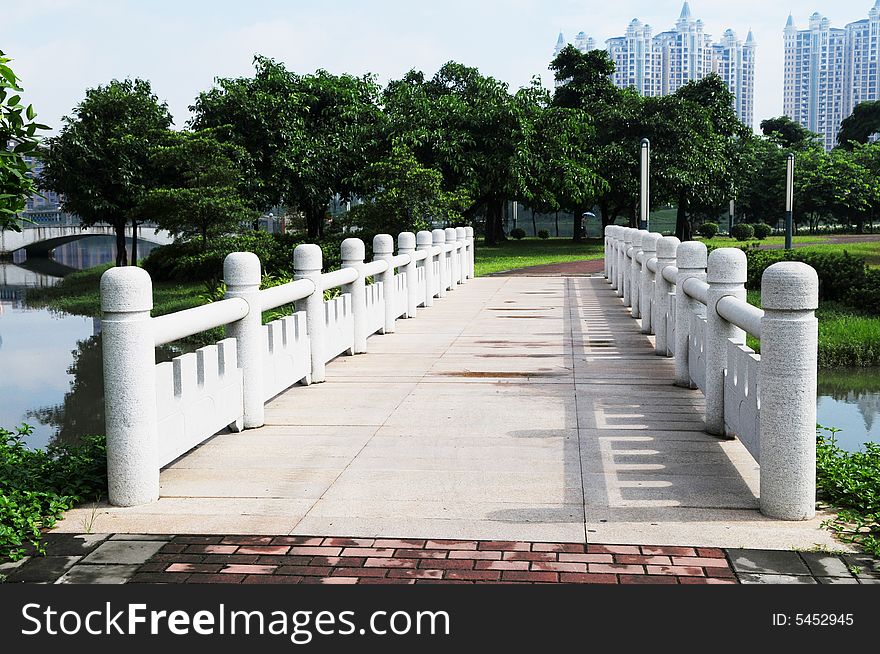 The bricked stone bridge with railings in a Chinese city park.