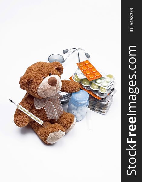 Doctor Teddy Bear with medical thermometer, pills and stethoscope