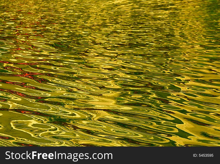 The golden water ripples in a small river. The golden water ripples in a small river.