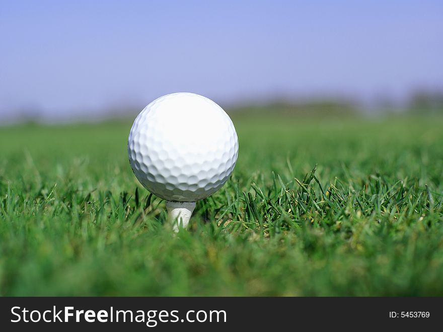 Golfball in front of the green grass hole. Golfball in front of the green grass hole