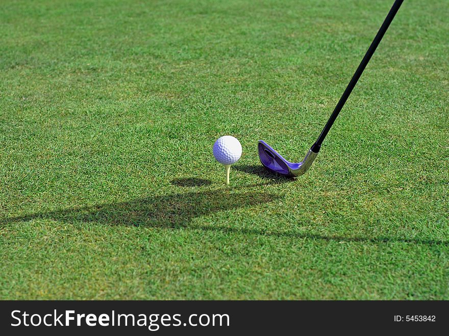 Golfball in front of the green grass hole. Golfball in front of the green grass hole