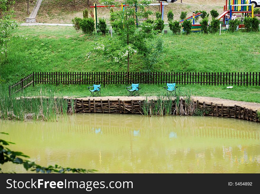 Folding blue chairs by muddy pond. Folding blue chairs by muddy pond