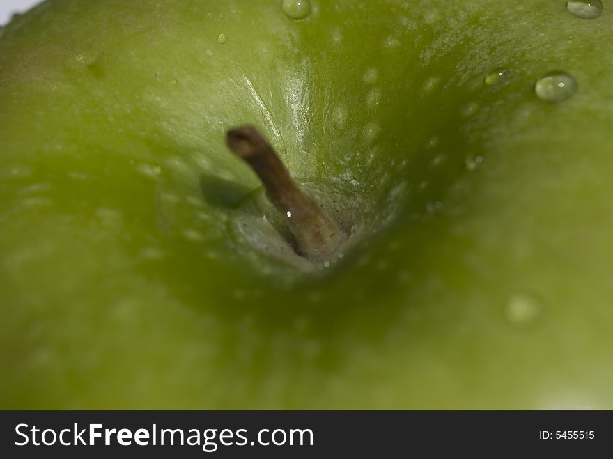 A closeup of a green apple with water droplets.