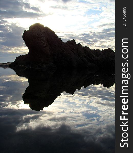 Rock reflection at sunset near the ocean